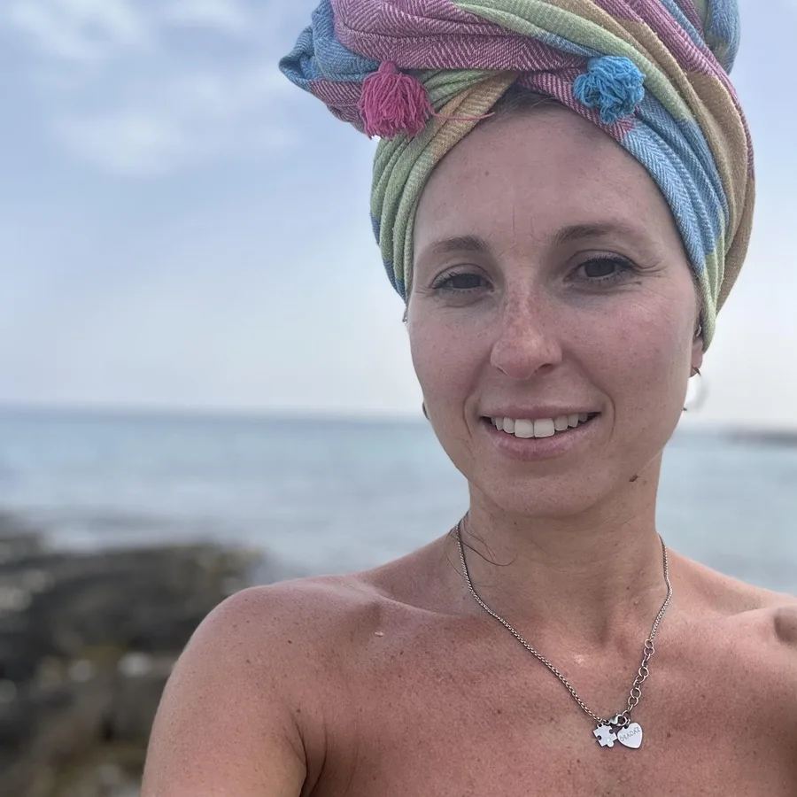 Mara Paradiso, la Regina del Bucato, sorride al mare con un asciugamano pastello avvolto sui capelli